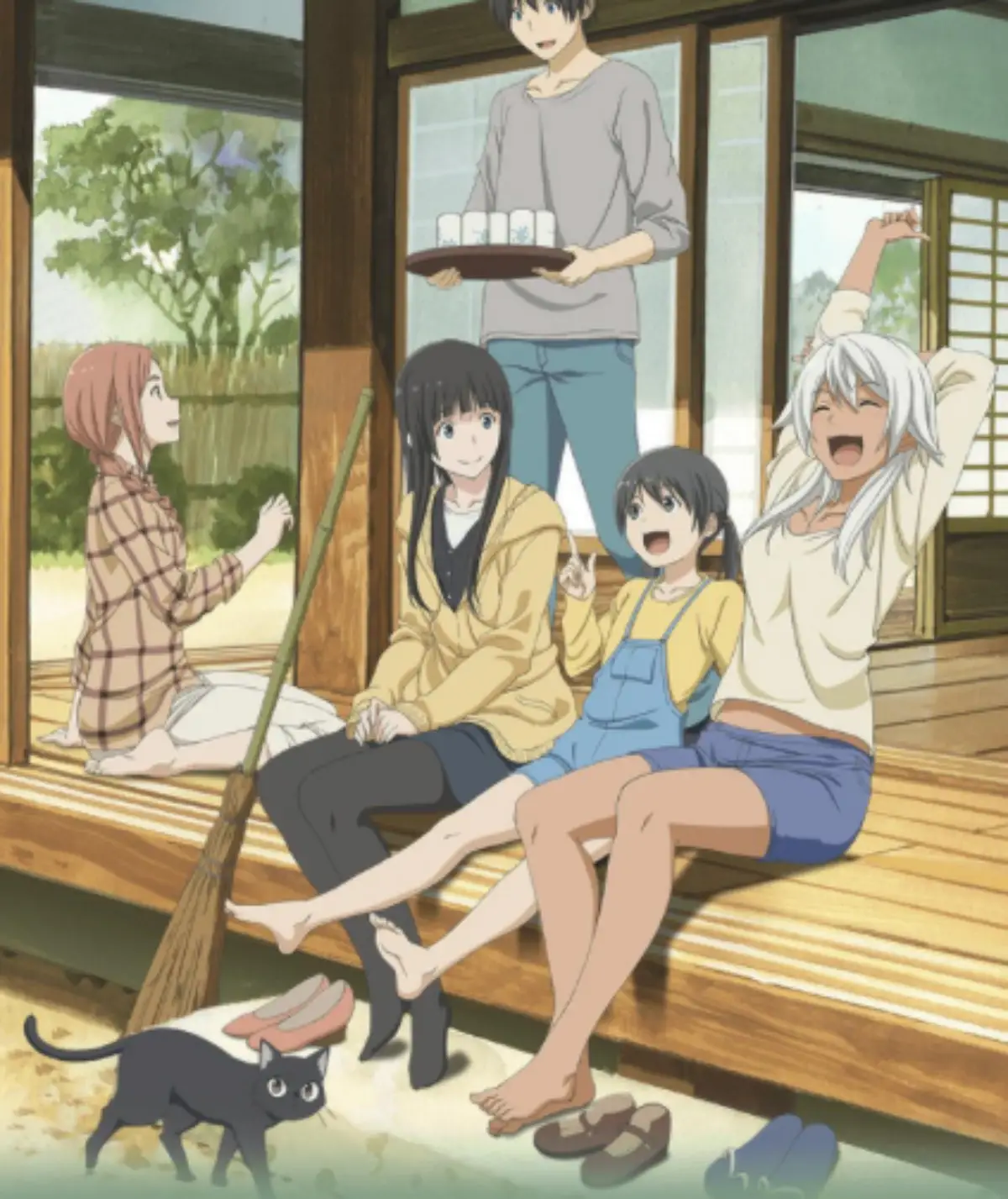 Group of friends relaxing on the veranda with tea, a cat nearby, enjoying countryside life.