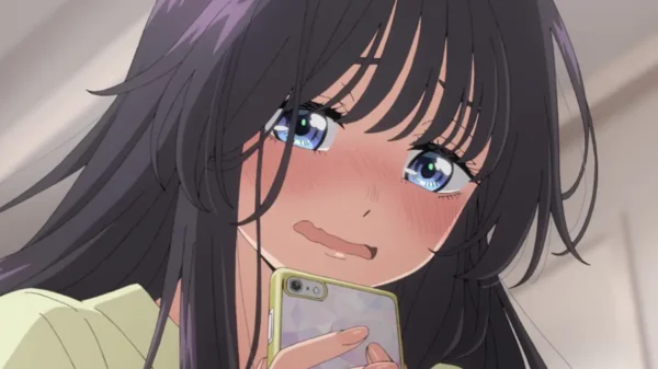 Close-up of a girl with long dark hair holding a phone, blushing nervously.