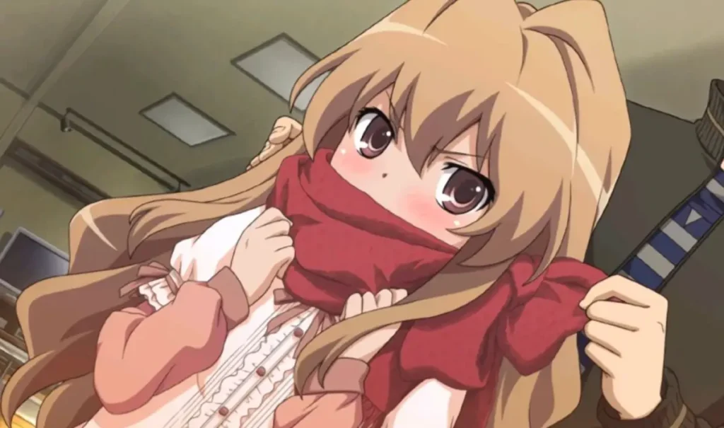 Small girl with long sandy hair blushes as a red scarf is wrapped around her neck.