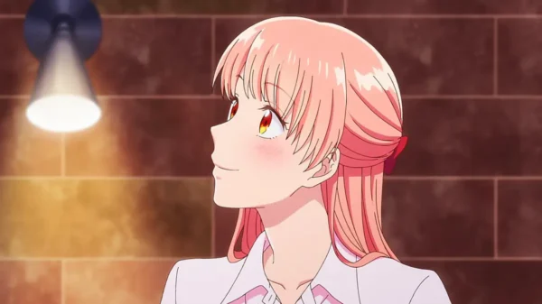 Narumi Momose smiling warmly under soft light with a blush on her face.