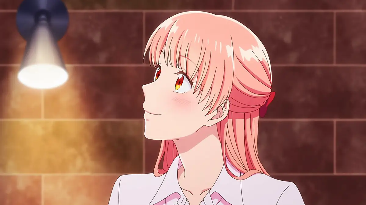 Narumi Momose smiling warmly under soft light with a blush on her face.
