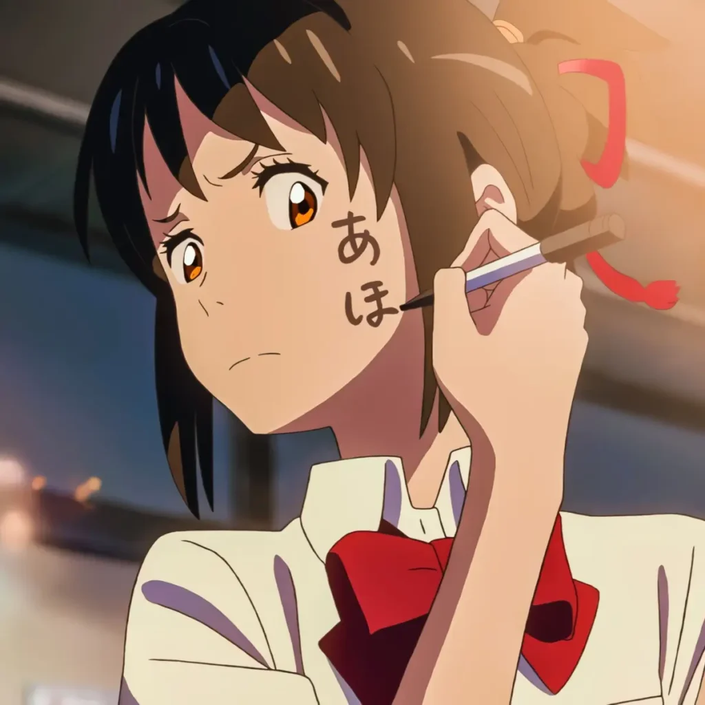 Mitsuha writing on her cheek with the word “aho” in Japanese.